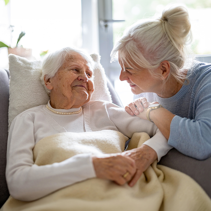 Eine ältere Dame mit einer ehrenamtlichen Betreuerin zu Hause.