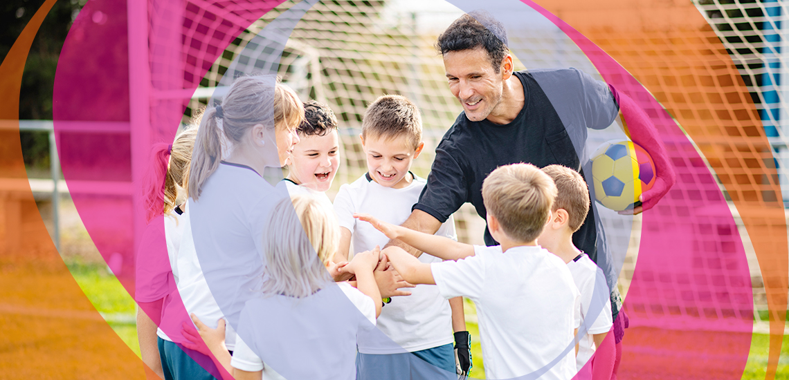 Ein erfahrener männlicher Trainer motiviert Jungen und Mädchen im Vorpubertätsalter mit einer Geste der übereinandergelegten Hände als Symbol der Teameinheit.